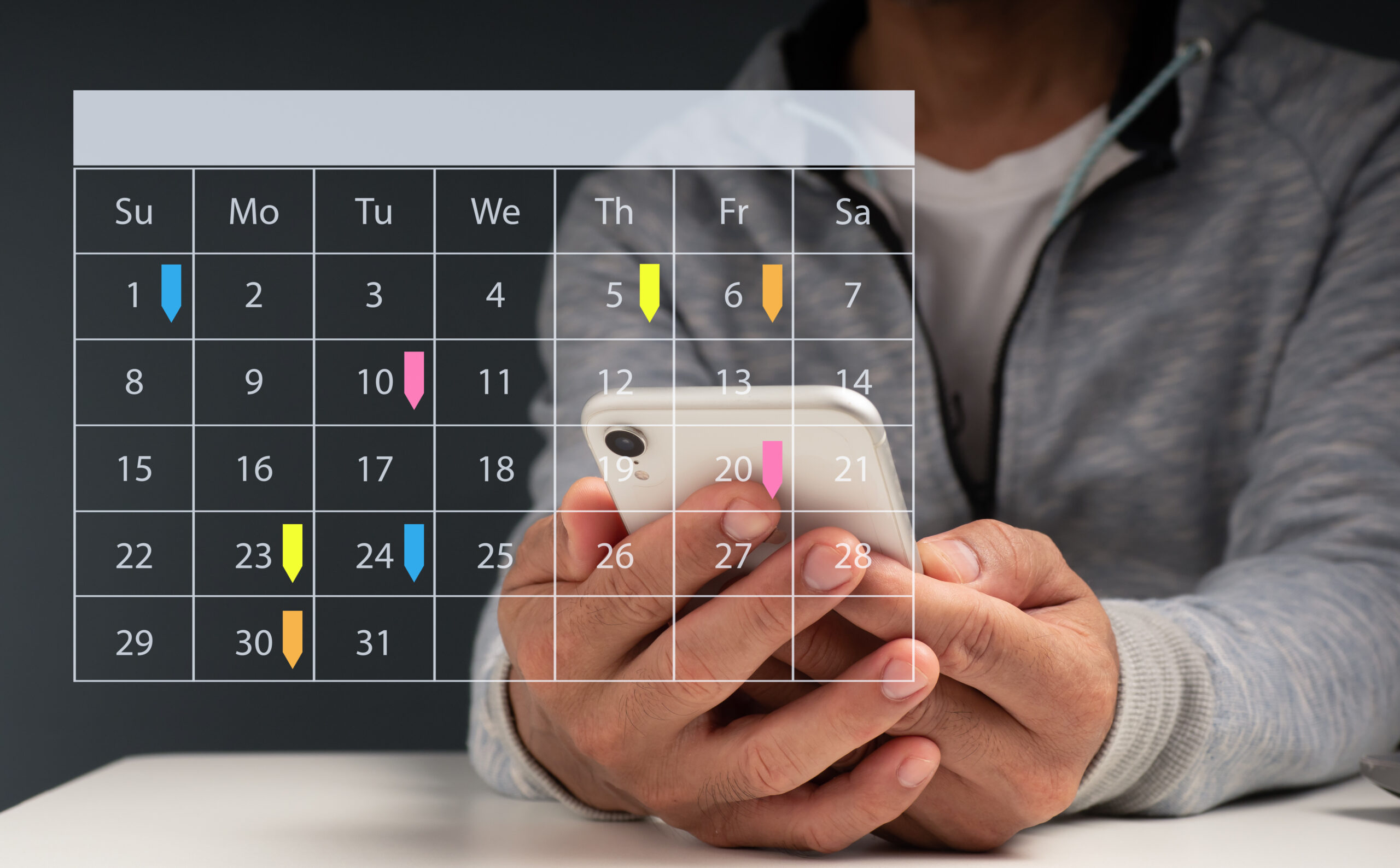 Hands holding a smartphone behind a monthly calendar overlay—visual for eliminating calendar chaos and choosing Gospel rest.