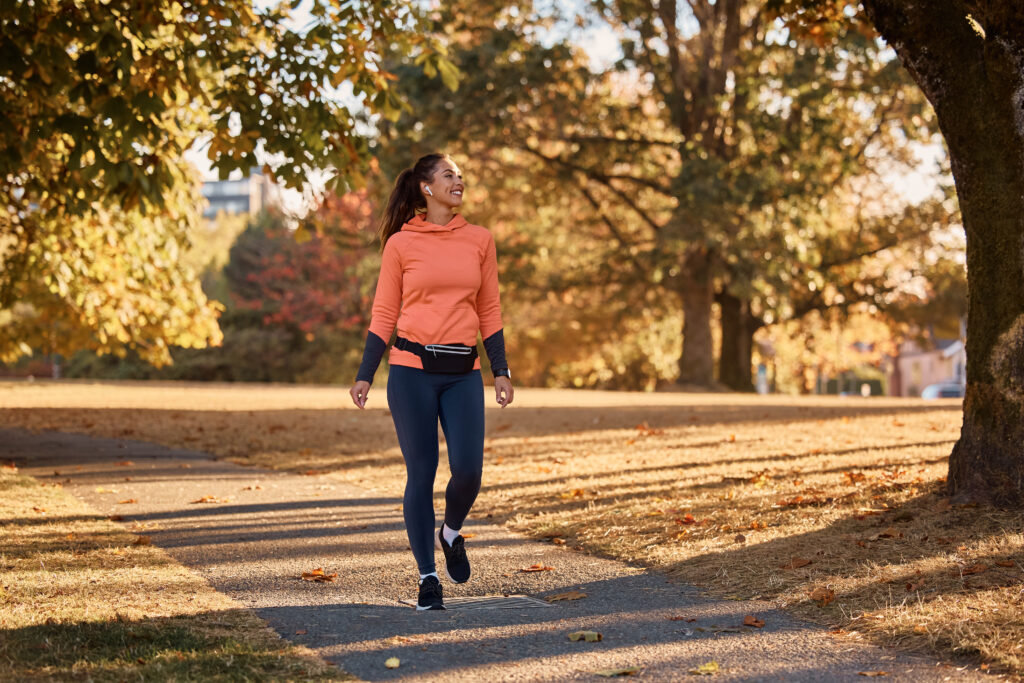 A homeschooling mother walks peacefully through a tree-lined park on an autumn morning, reflecting the calm pace of the Provision Over Pressure homeschool rhythm.