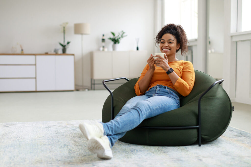 Peaceful mother relaxing in green chair with mug, practicing a Christian sabbatical at home