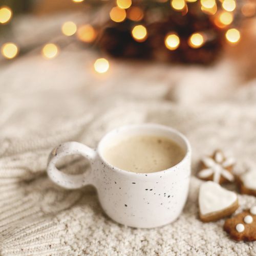 Cozy winter mug on a soft blanket beside Christmas cookies, symbolizing restful homeschool planning.