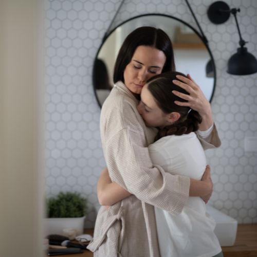 A mother gently embracing her teenage daughter in a calm home setting, expressing comfort and connection during a challenging homeschool moment.