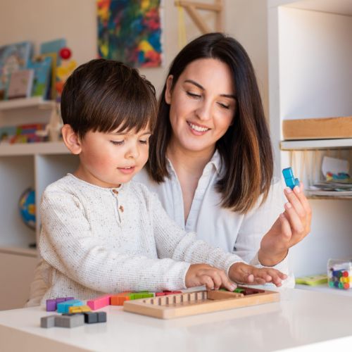 A mother sits beside her young child during a gentle homeschool Kindergarten lesson, illustrating the calm, hands-on rhythm of a gentle kindergarten homeschool curriculum.