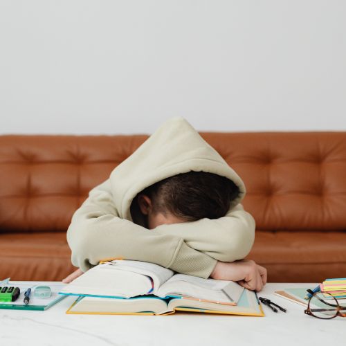 A discouraged student rests his head on an open book, illustrating the overwhelm that leads families to seek homeschool grade placement without testing.