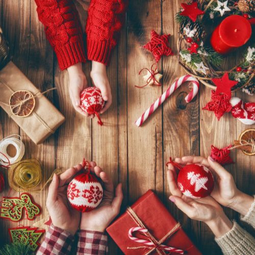 Hands holding red Christmas ornaments during a family craft time, symbolizing a peaceful Advent homeschool rhythm.