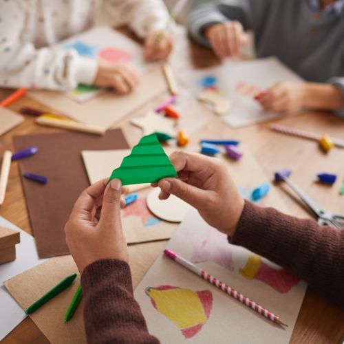 Hands working on simple Christmas crafts during a winter homeschool creativity session.