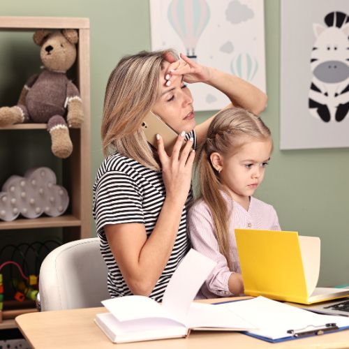 A mother overwhelmed by homeschool choices while helping her young child with schoolwork at the table